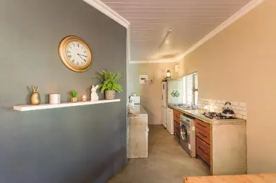a kitchen with a clock on the wall at Steenbok farm cottages Aalwyn Cottage in Wolseley
