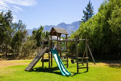 a playground with a slide in the grass at Steenbok farm cottages Aalwyn Cottage in Wolseley