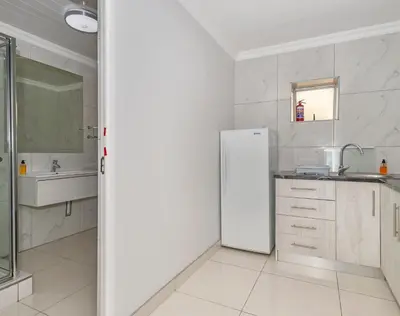 a white kitchen with a refrigerator and a sink at Ocean Way Villas - Self Catering in Cape Town