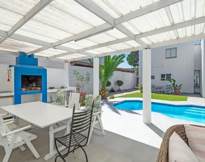 a patio with a table and chairs and a swimming pool at Ocean Way Villas - Self Catering in Cape Town