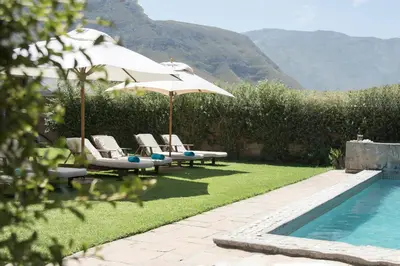 a pool with umbrellas and lounge chairs next to a pool at The Yacht in Hermanus