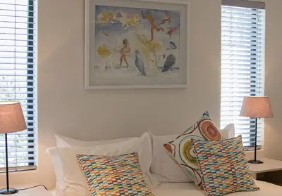 a white couch with pillows and a painting on the wall at The Yacht in Hermanus