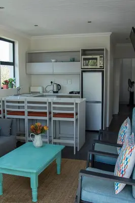 a kitchen and living room with a table and a refrigerator at The Yacht in Hermanus