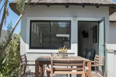 a patio with a table and chairs and a window at The Yacht in Hermanus