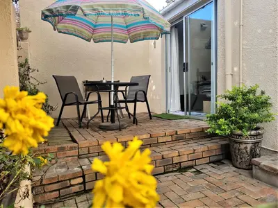 a patio with a table and chairs and an umbrella at Walters Lane Economy Apartment 1 - No Loadshedding in Cape Town