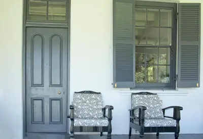 two chairs sitting in front of a house with a door at Verandah House in Hermanus