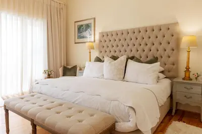 a bedroom with a large white bed with a large padded headboard at Villa Puccini in Cape Town