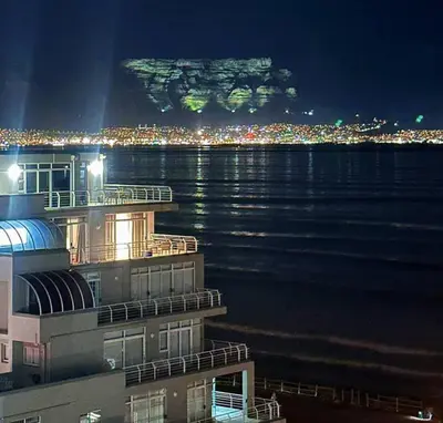 a view of a city at night with a mountain at Seaview Kite Beach Holiday Apartment in Cape Town