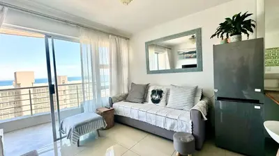 a living room with a couch and a large window at Seaview Kite Beach Holiday Apartment in Cape Town