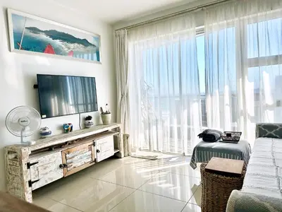 a living room with a tv and a large window at Seaview Kite Beach Holiday Apartment in Cape Town