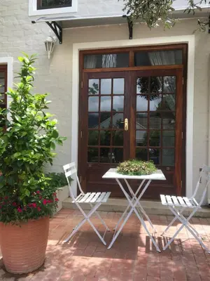 a patio with two chairs and a table in front of a door at Protea Studio Franschhoek Central in Franschhoek