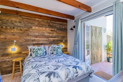 a bedroom with a wooden accent wall and a bed at Protea Room Franschhoek Central in Franschhoek
