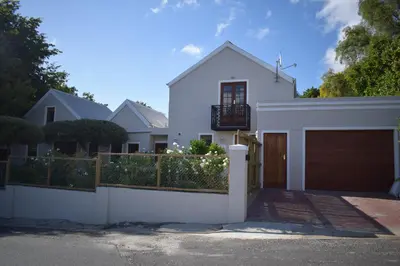 a white house with a gate and a garage at Protea Room Franschhoek Central in Franschhoek