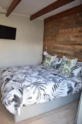 a bed with a black and white comforter and pillows at Protea Room Franschhoek Central in Franschhoek