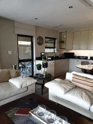a living room with two white couches and a kitchen at Vrede Selfcatering in Somerset West