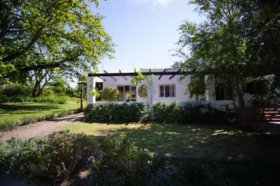 a white house with a fence and a yard at Klein Welmoed Luxury Guest House in Stellenbosch