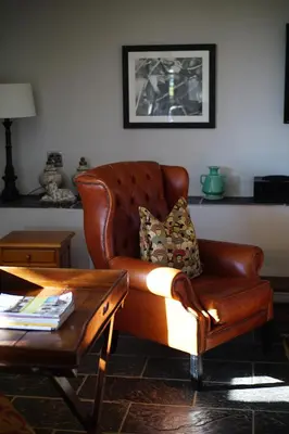 a brown leather couch in a living room with a table at Klein Welmoed Luxury Guest House in Stellenbosch