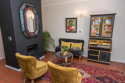 a living room with a table and chairs and a mirror at Baruch Guest House Rhodes in Stellenbosch