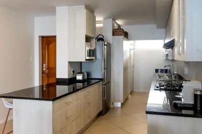 a kitchen with black counter tops and a refrigerator at Bayview 208 in Hermanus
