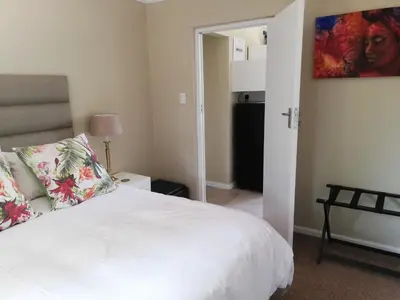 a bedroom with a bed with a white bedspread at Little Elm Cottage in Cape Town