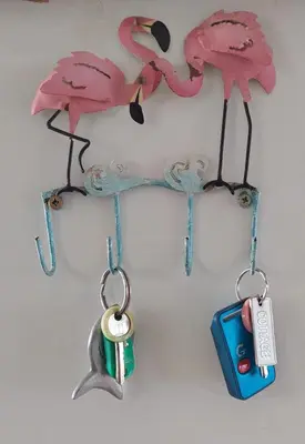two pink flamingos hanging on a wall with a cell phone at The Amaryllis Luxury Apartment Bella Donna in Bettyʼs Bay