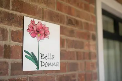 a sign on a brick wall with a flower on it at The Amaryllis Luxury Apartment Bella Donna in Bettyʼs Bay