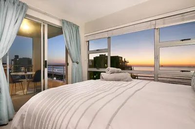 a bedroom with a white bed and a large window at Ocean View A603 in Cape Town