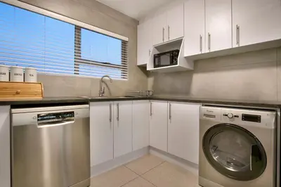 a kitchen with a washing machine and a sink at Ocean View A603 in Cape Town
