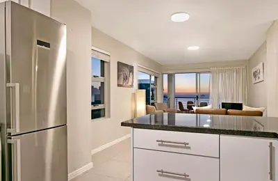 a kitchen with a refrigerator and a living room at Ocean View A603 in Cape Town