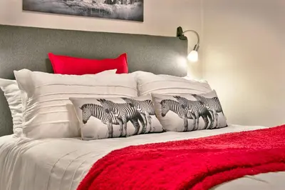 a bed with white pillows and a red head board at Ocean View A603 in Cape Town