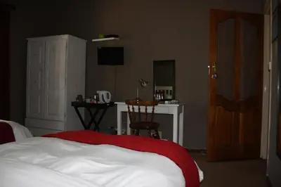 a bedroom with a bed and a desk and a television at The Vinelands on Alpha Guest House in Cape Town
