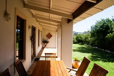 a wooden table and chairs on the porch of a house at Hilton House in Pringle Bay