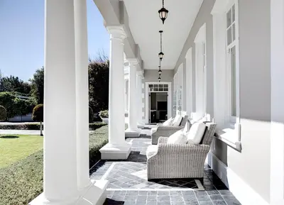 a porch with white chairs and columns on a house at Banksia Boutique Hotel & Spa in Cape Town