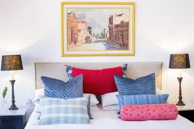 a bedroom with a bed with pillows and a painting on the wall at Maison Montagne in Franschhoek