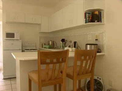 a kitchen with two chairs at a kitchen counter at Bradclin Sport Newlands in Cape Town