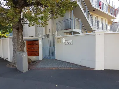 a white building with a door and a tree at Bradclin Sport Newlands in Cape Town