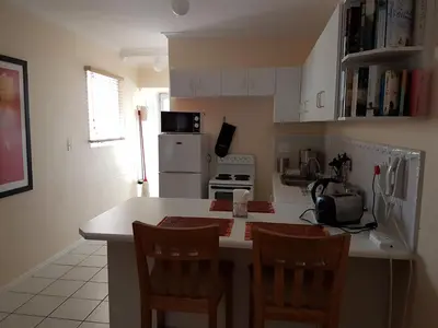 a kitchen with a counter with chairs and a refrigerator at Bradclin Sport Newlands in Cape Town