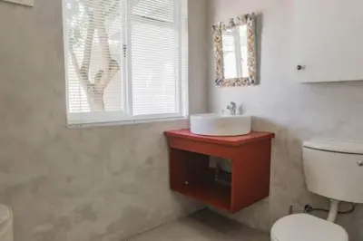a bathroom with a sink and a toilet and a window at Angel's Place by the Sea in Hermanus
