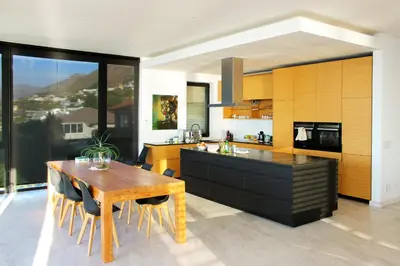 a kitchen with a wooden table and a dining room at Redrock Ocean View Villa in Cape Town