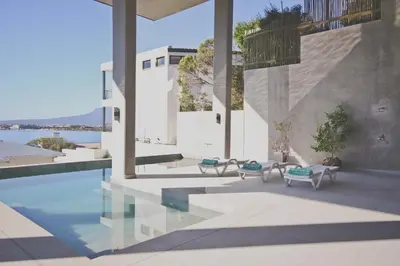 a house with a pool and two benches next to it at Redrock Ocean View Villa in Cape Town