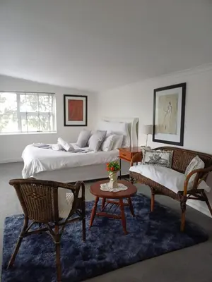 a bedroom with two beds and a couch and a table at sunny get away for a family of 4 in Cape Town