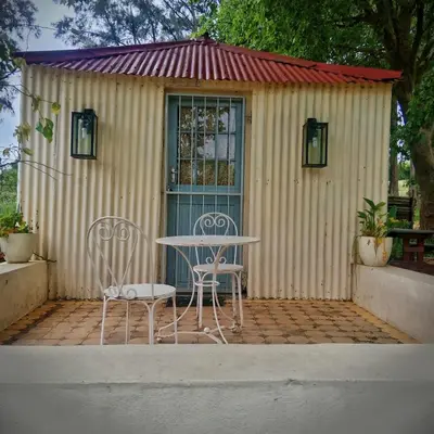 a table and chairs in front of a shed at Cabernet Cottage Be Still and Know in Franschhoek