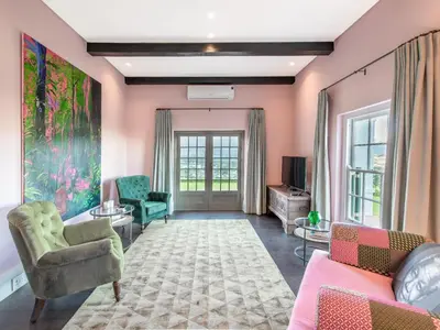 a living room with pink walls and green chairs at The Vineyard Cottage by L' Amitie Estate in Franschhoek
