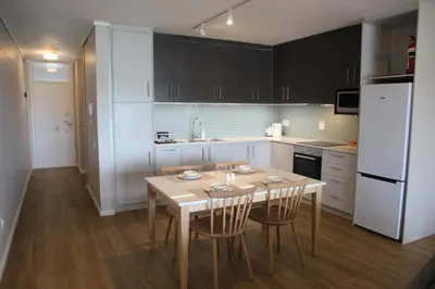 a kitchen with a table and chairs and a white refrigerator at The Boardwalk Accommodation in Gordonʼs Bay