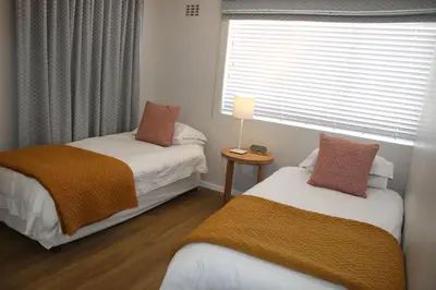 two beds in a small room with a window at The Boardwalk Accommodation in Gordonʼs Bay