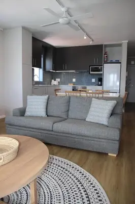 a living room with a couch and a kitchen at The Boardwalk Accommodation in Gordonʼs Bay