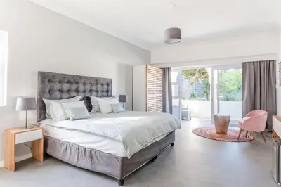 a white bedroom with a large bed and a window at The Views Guesthouse in Somerset West