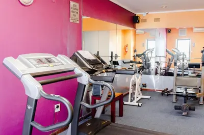 a gym with several tread machines and a pink wall at Strand Pavilion in Strand