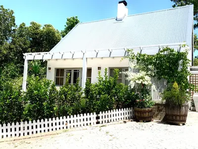 a white house with a white picket fence at One Oak Guest House in Somerset West