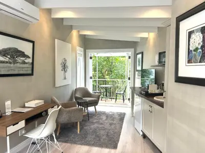 a kitchen with a desk and chairs and a table at One Oak Guest House in Somerset West